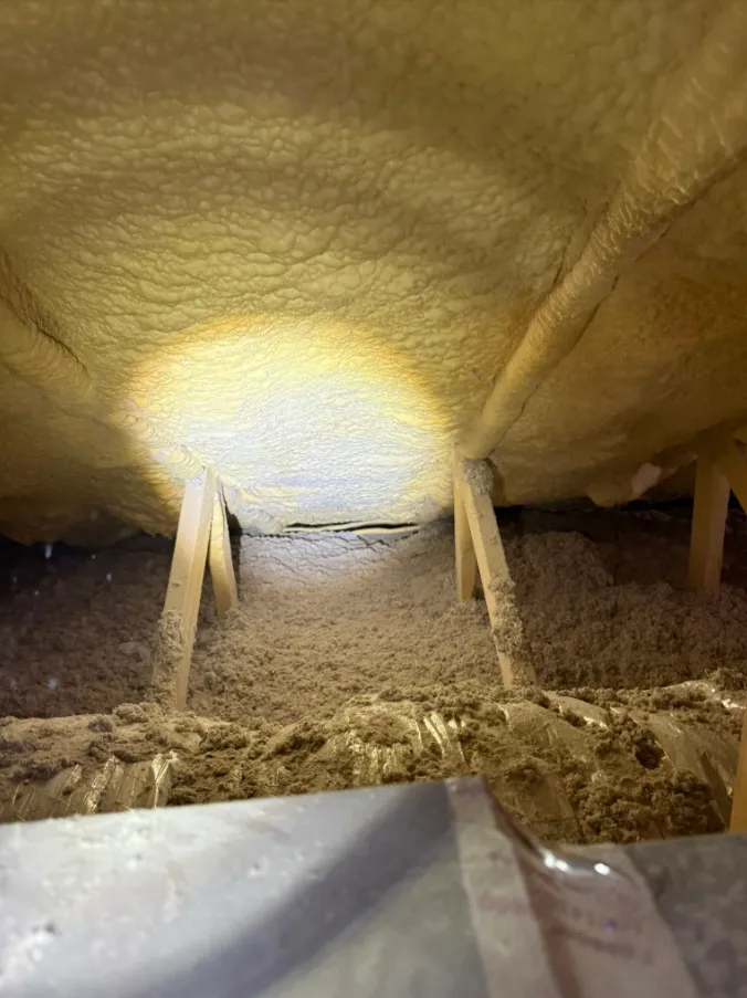 Thin spray foam layer above cellulose insulation — the previous installer's 'fix' that created a moisture trap and started mold growth