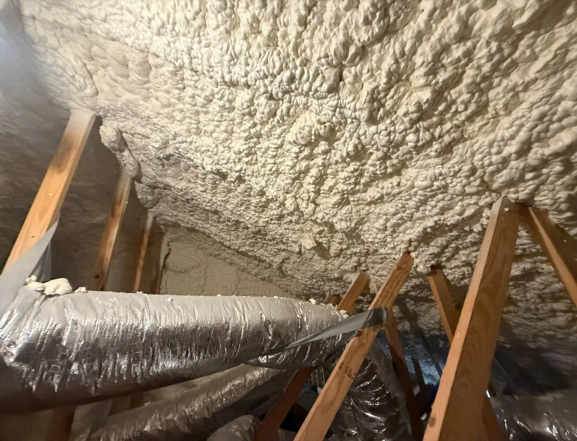 HVAC ducts running through a sealed attic after spray foam retrofit — ducts now sit in conditioned space instead of a 150°F attic