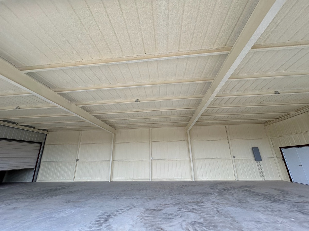 Metal building interior with clean closed cell spray foam finish on ceiling and walls — ready for use.