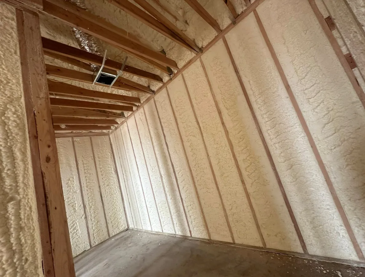 After spray foam retrofit: clean, consistent closed-cell foam between rafters — a sealed conditioned attic envelope