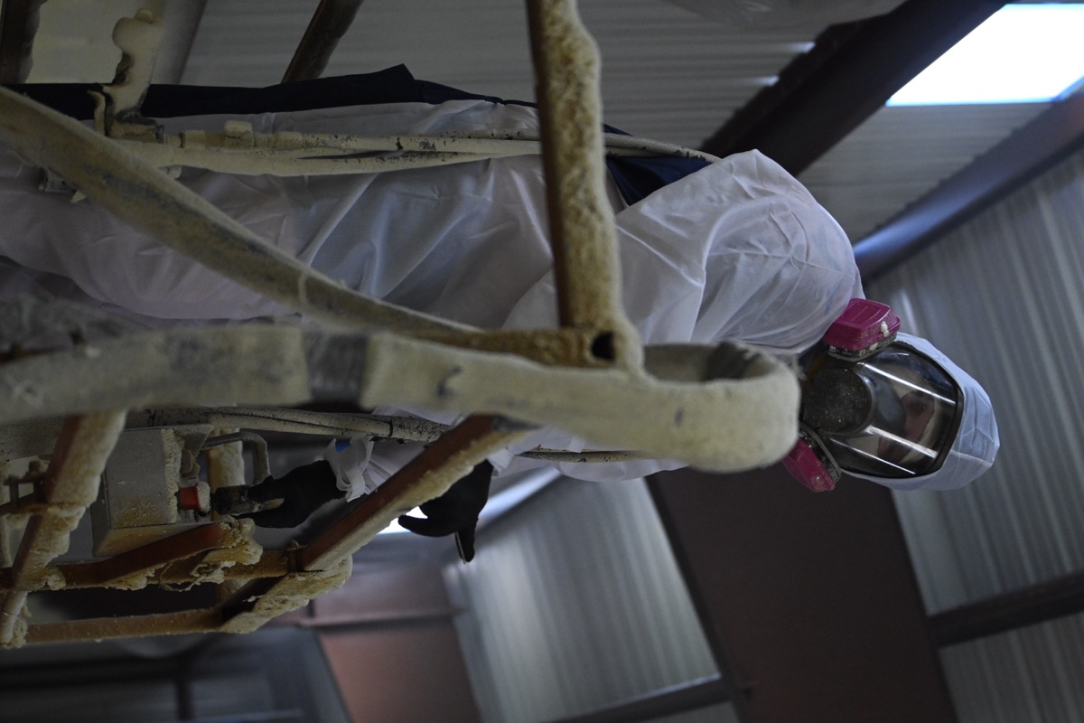 A spray foam crew member with professional equipment inside a metal building, ready for insulation application.