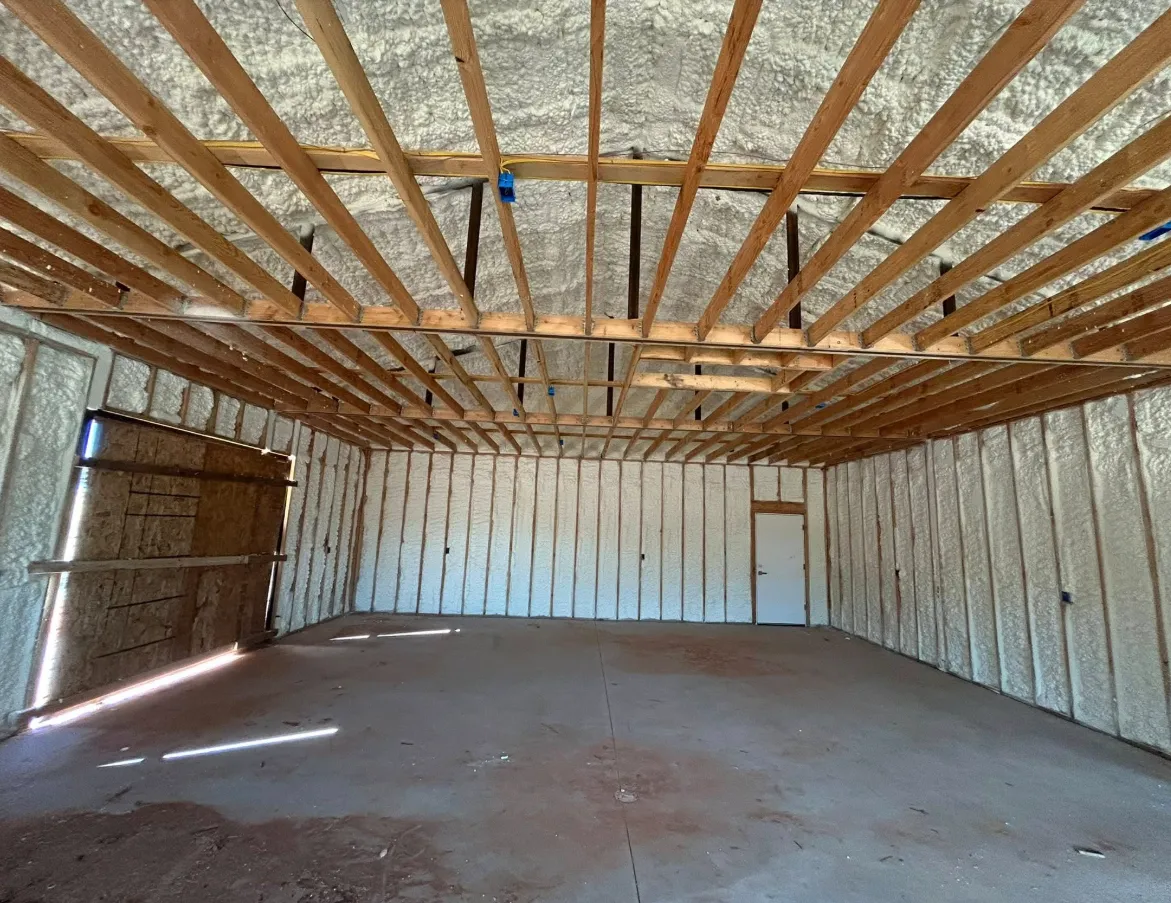 Wide-angle view of a completed spray foam installation — clean walls, sealed roof deck, fully conditioned space