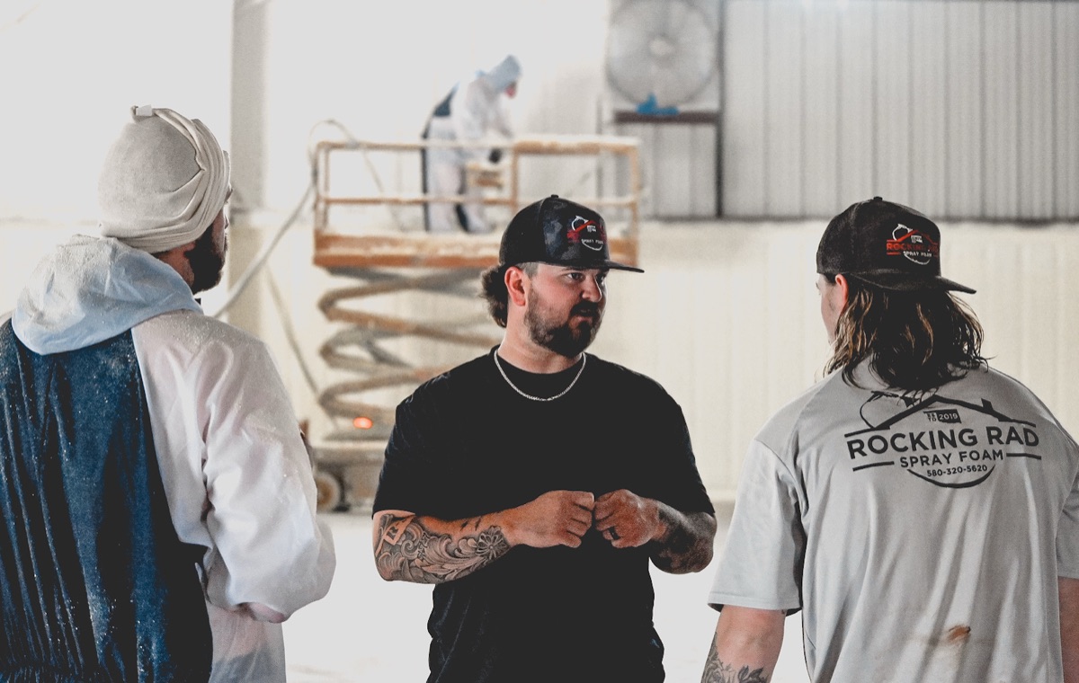 Rocking Rad crew working inside a metal building — spray foam application in progress.